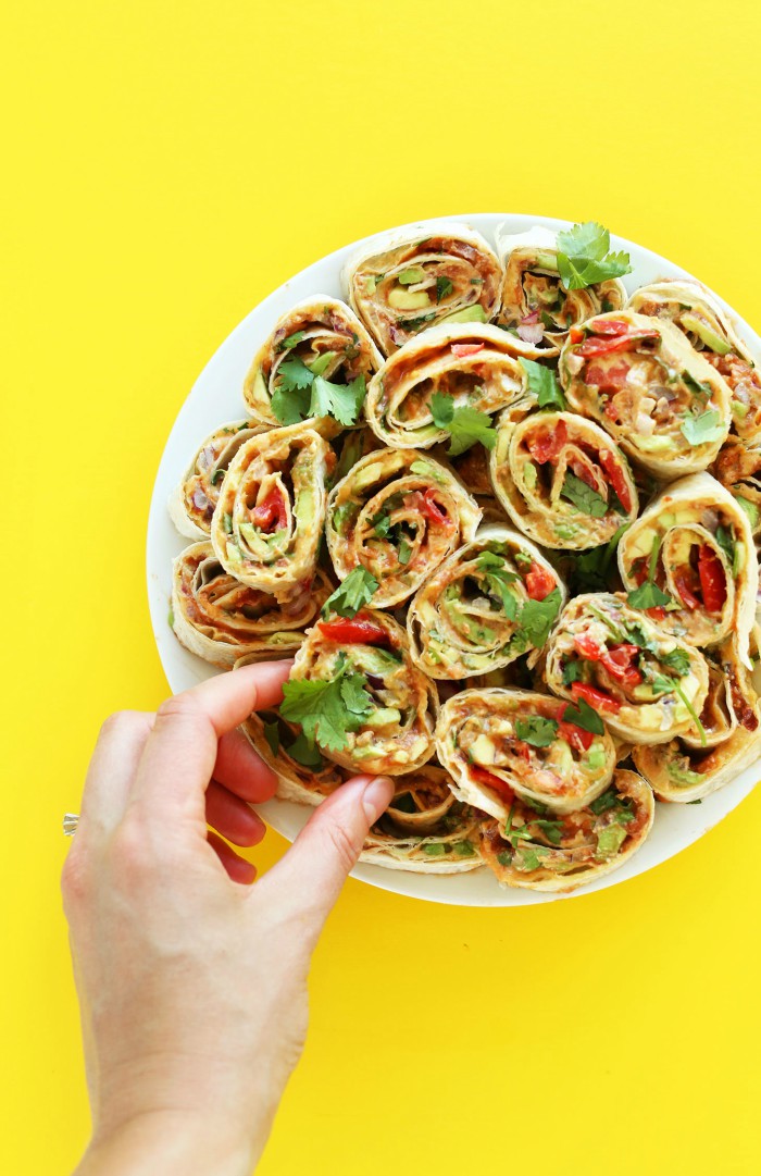 hand grabbing 6-layer Mexican easy pinwheels on a plate