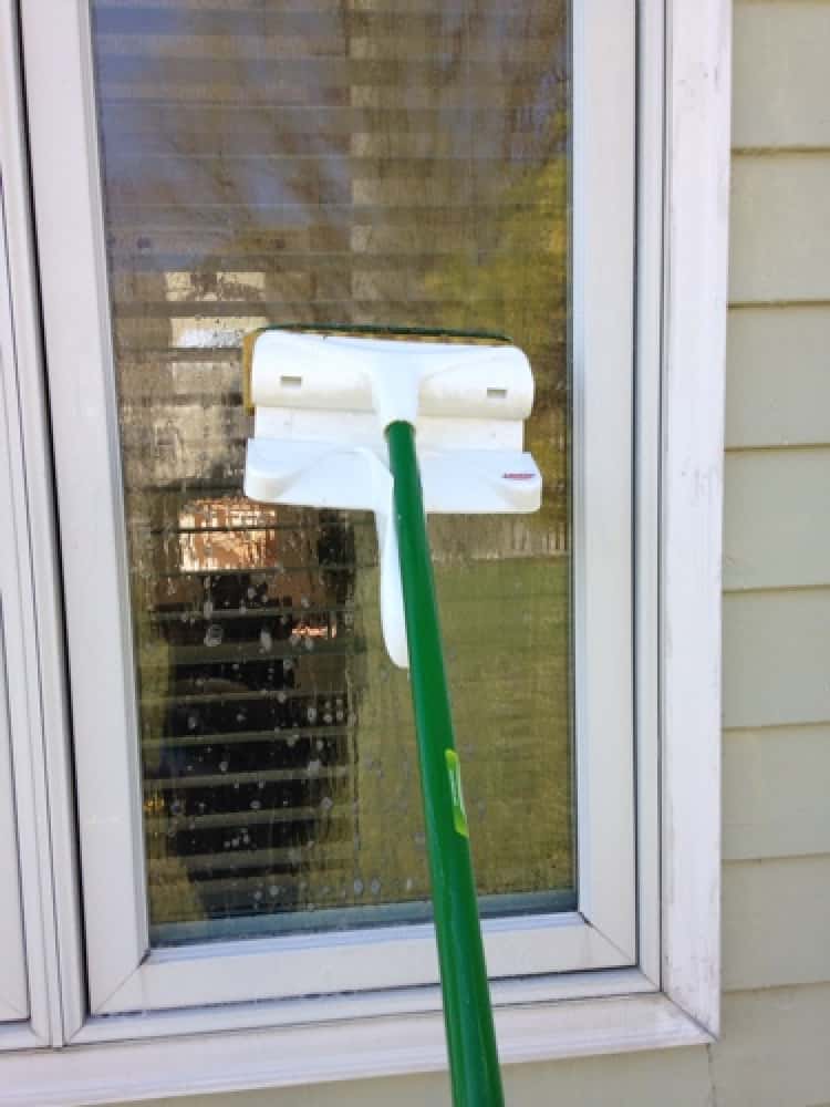 Washing windows with a long-handled brush 