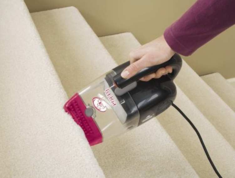 Handheld Bissel pet hair eraser: woman using handheld Bissel on the stairs