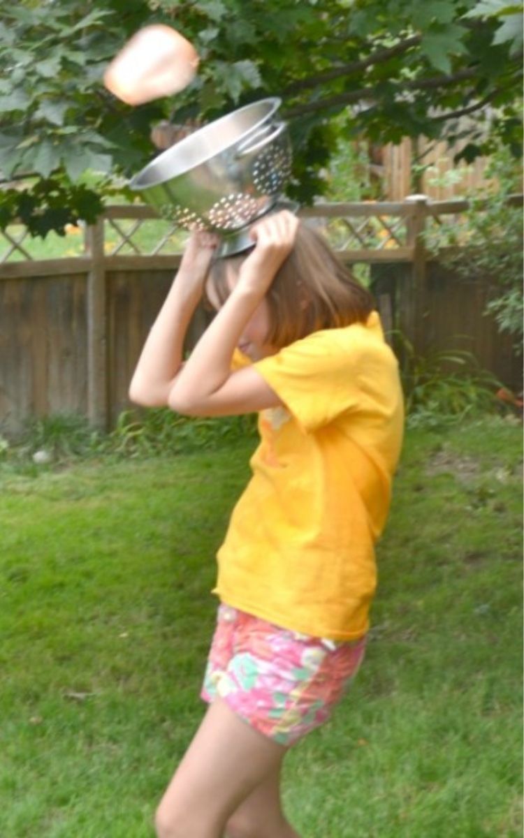 Girl carrying colander on her head for a water balloon game