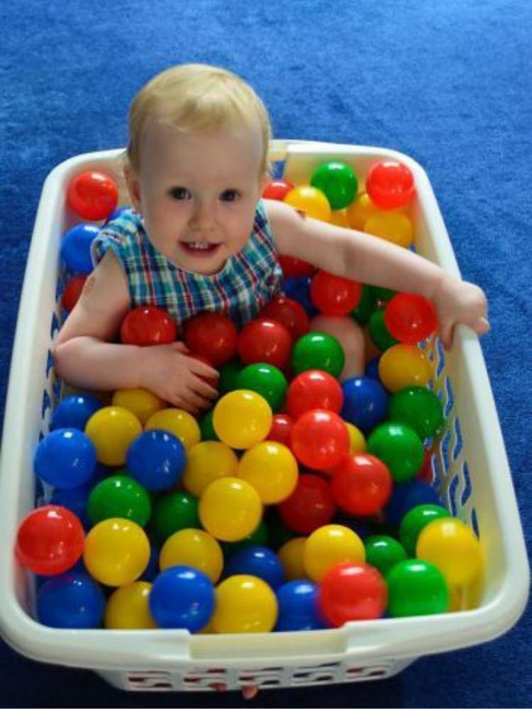 Picture of baby playing with balls in a laundry basket