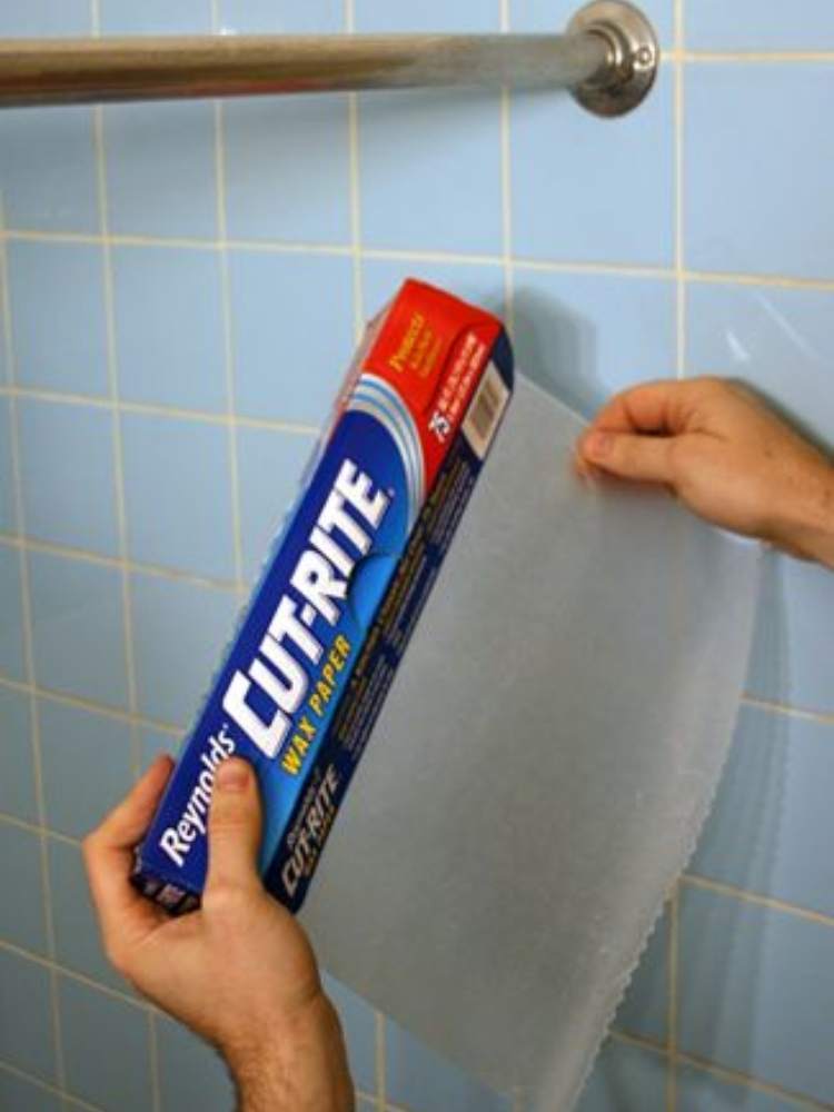 Picture of wax paper being used to clean shower curtain rod