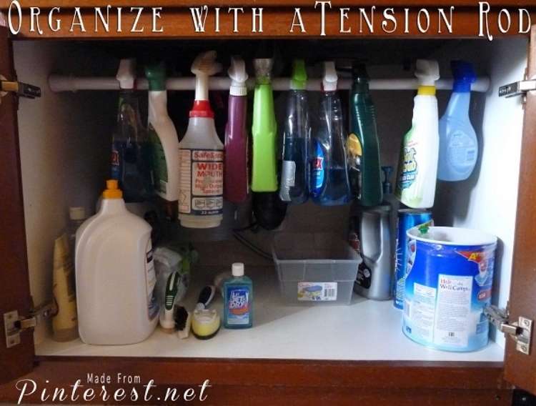 OneCrazyHouse How to Organize Kitchen Cabinet under sink open, revealing a tension rod holding all spray cleaning bottles.