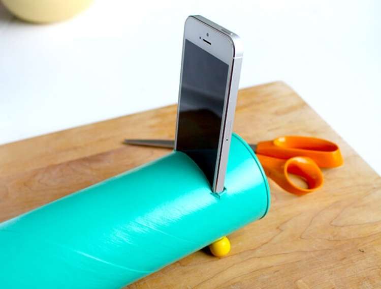 Pringles can painted and made into a speaker for smartphone with smartphone coming out of hole, scissors in background