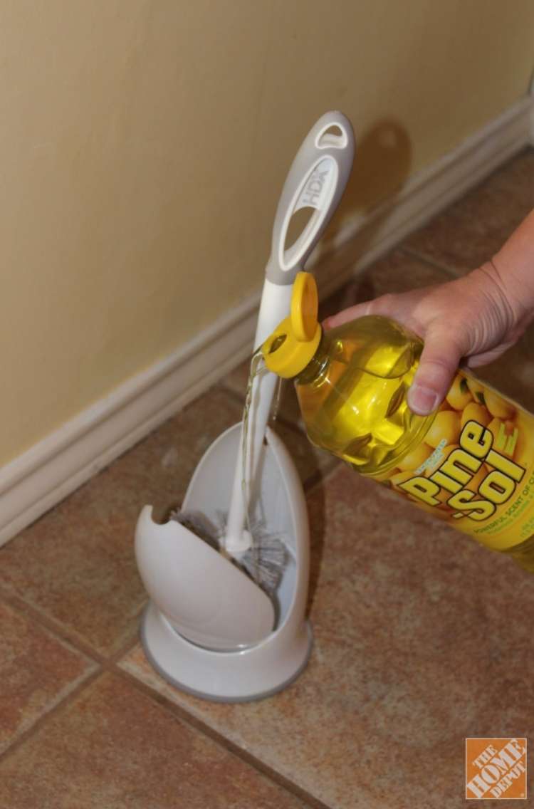 Hand pouring pinesol into an open toilet brush holder