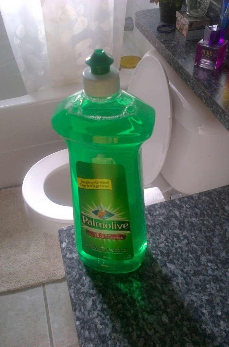 Bottle of dish soap sitting on bathroom counter with toilet in background