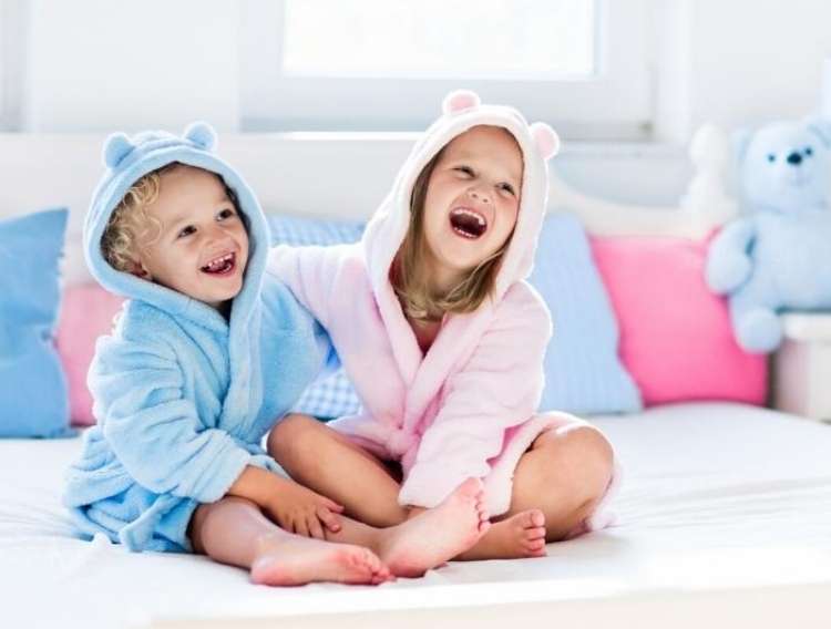 OneCrazyHouse recycled towels  2 kids smiling sitting on carpeted floor wearing hooded towels. 