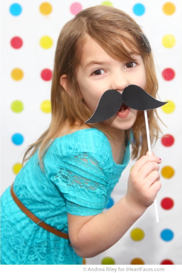 photo booth props for parties - girl hold a mustache prop for a photo booth