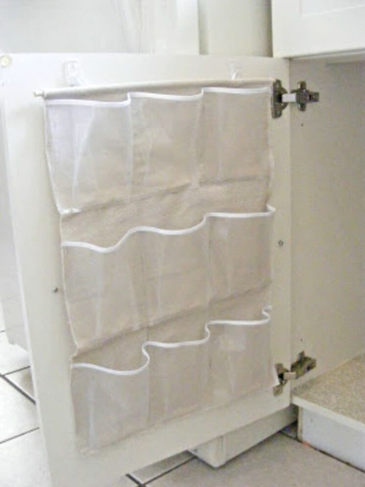 Under bathroom sink storage - small shoe organizer hung on the back of the bathroom cabinet door for easy storage