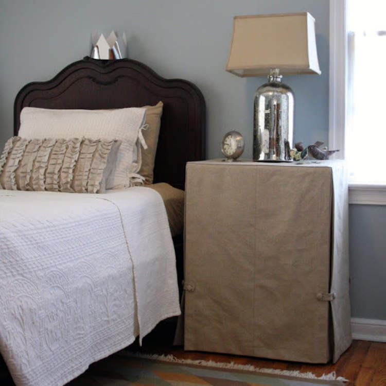 Hidden storage created by hiding a bedside table under a fabric skirt.
