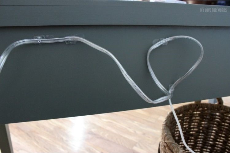 Command hooks attached to the back of a table to hide a lamp cord and manage cables