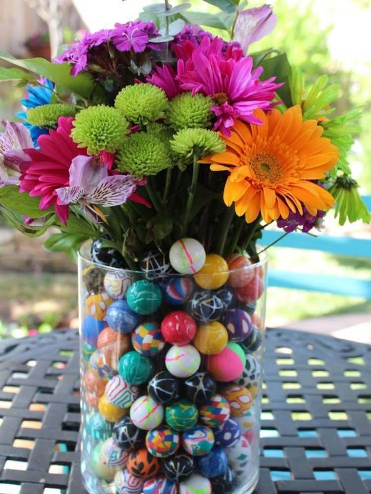 Picture of vase filled with colorful toy bouncy balls and flowers