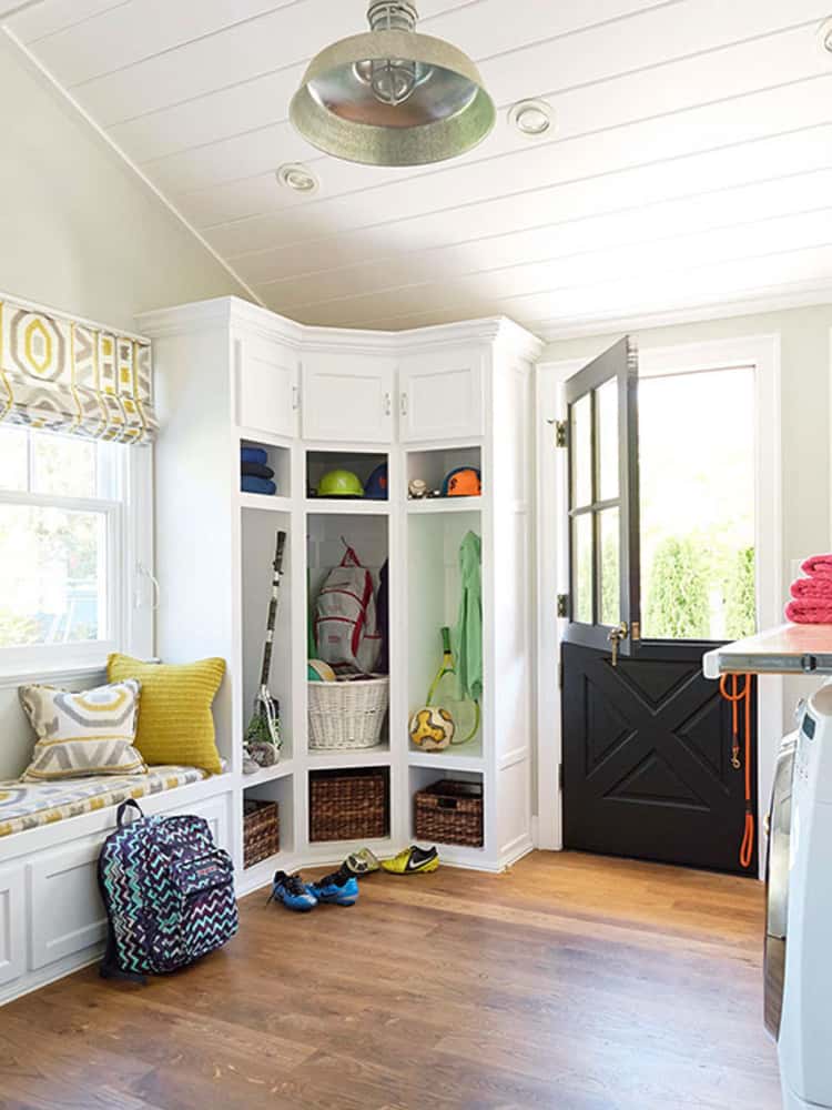 white corner storage area in the entryway, with baskets, cabinets and a hanging area