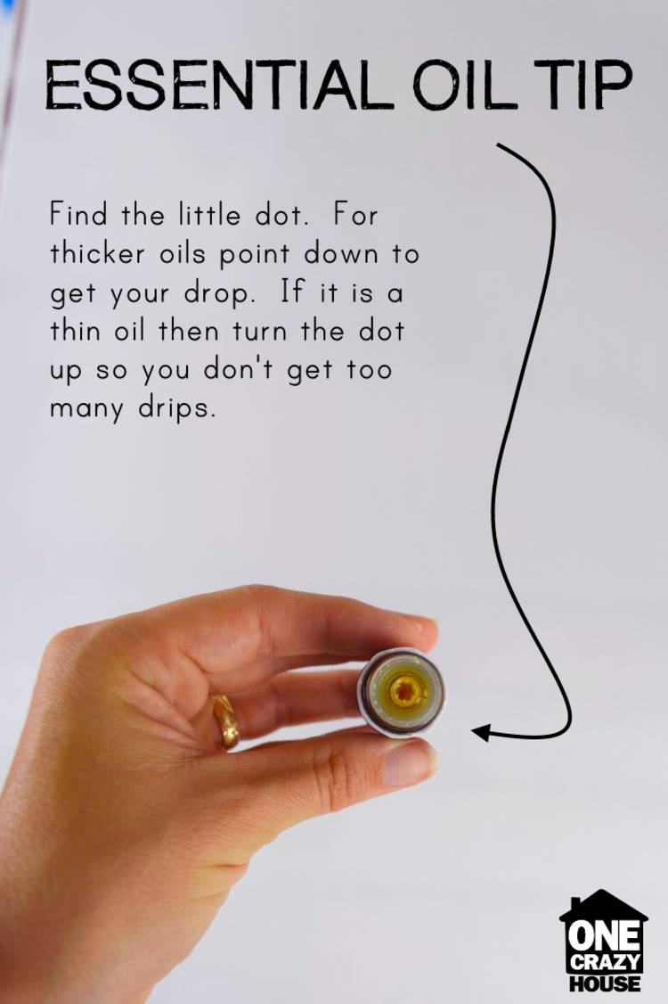 Genius essential oils tips and tricks - image of a hand holding an essential oil bottle sideways so you can see the inner lid, and the words, "essential oil tip - find the dot. For thicker oils point down to get your drop. If it is a thin oil then turn the dot up so you don't get too many drips."