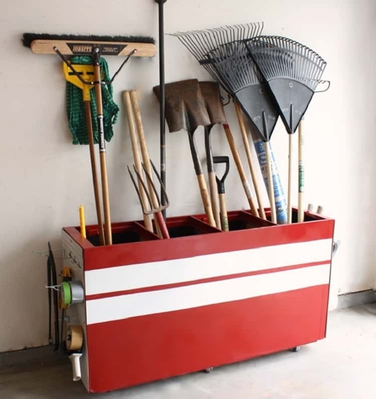 garden tool organization with an old file cabinet turned on it's side and painted red, holding long garden tools upright