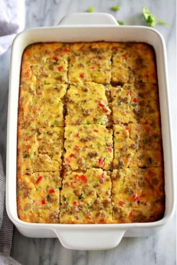 White casserole dish containing breakfast casserole made with eggs and red and green vegetables