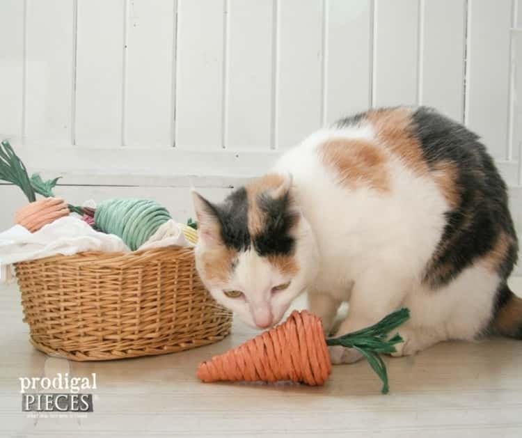a cat playing with one of it's DIY paper mache cat toys that resembles a carrot