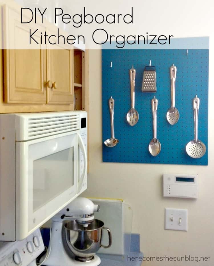 blue pegboard hanging on kitchen wall with spoons hanging on it, a microwave to the left of it