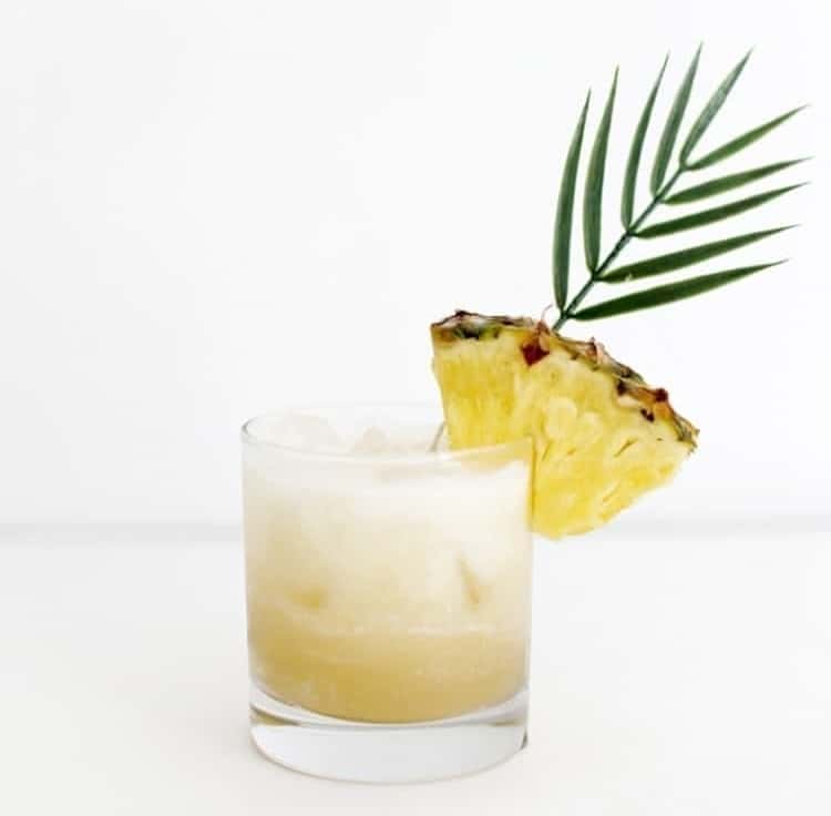 Pina Colada Spritzer mocktail garnished with a pineapple slice
