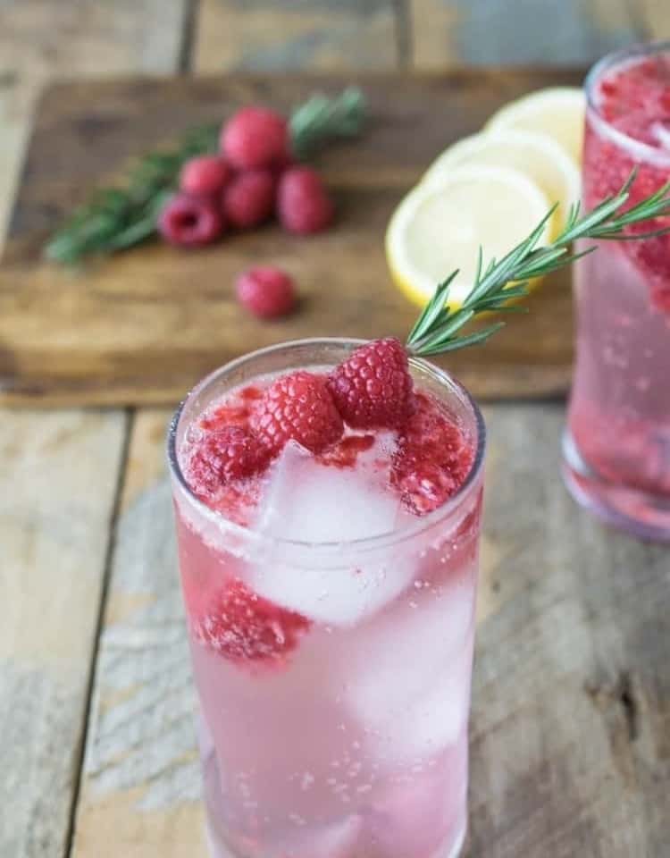 Raspberry Rosemary Spritzer mocktail garnished with raspberries and a sprig of rosemary