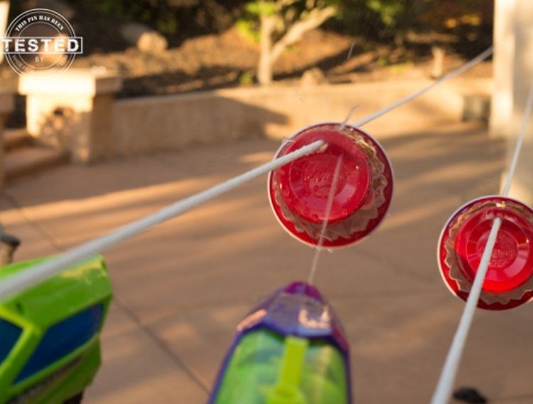 watergun shooting at red paper plates tied to a string