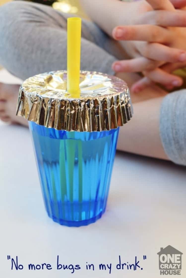 A cupcake liner placed on a cup to keep bugs off the drink with a straw inserted through the cupcake liner
