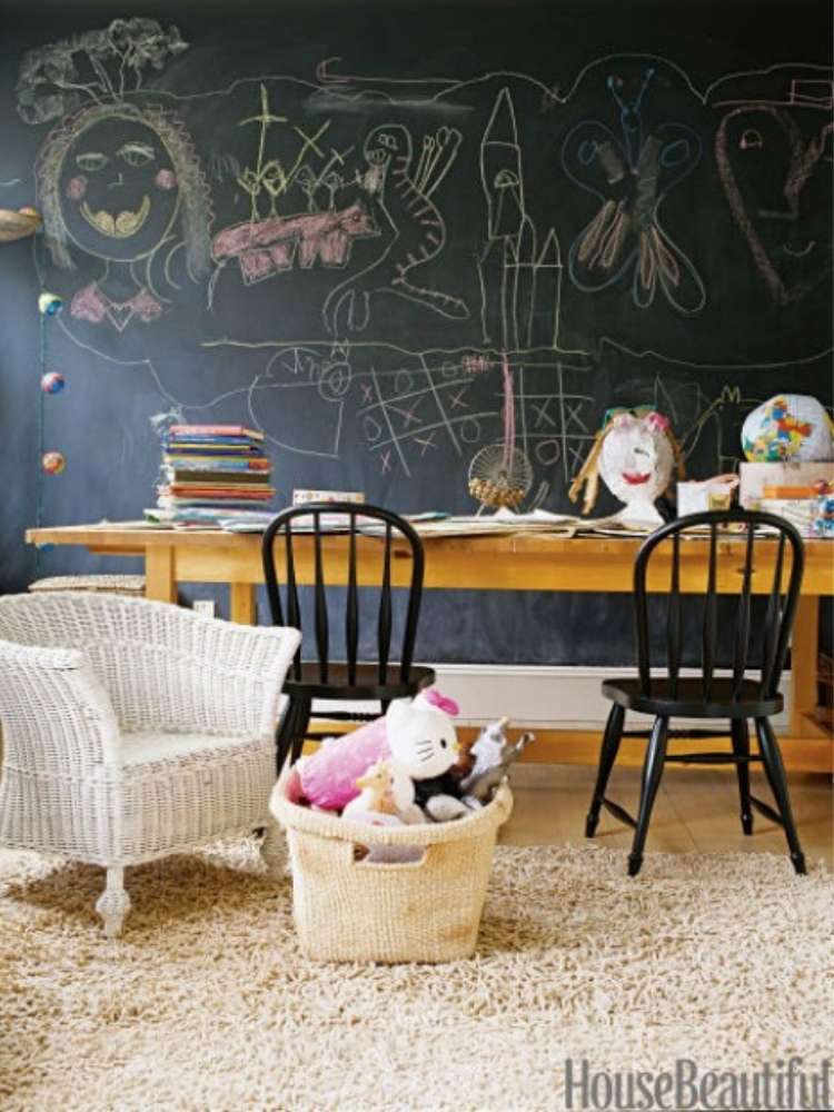 OneCrazyHouse kid friendly living room ideas wall covered in chalboard paint with chalk drawings with a table in front of wall, arm chair off to the side