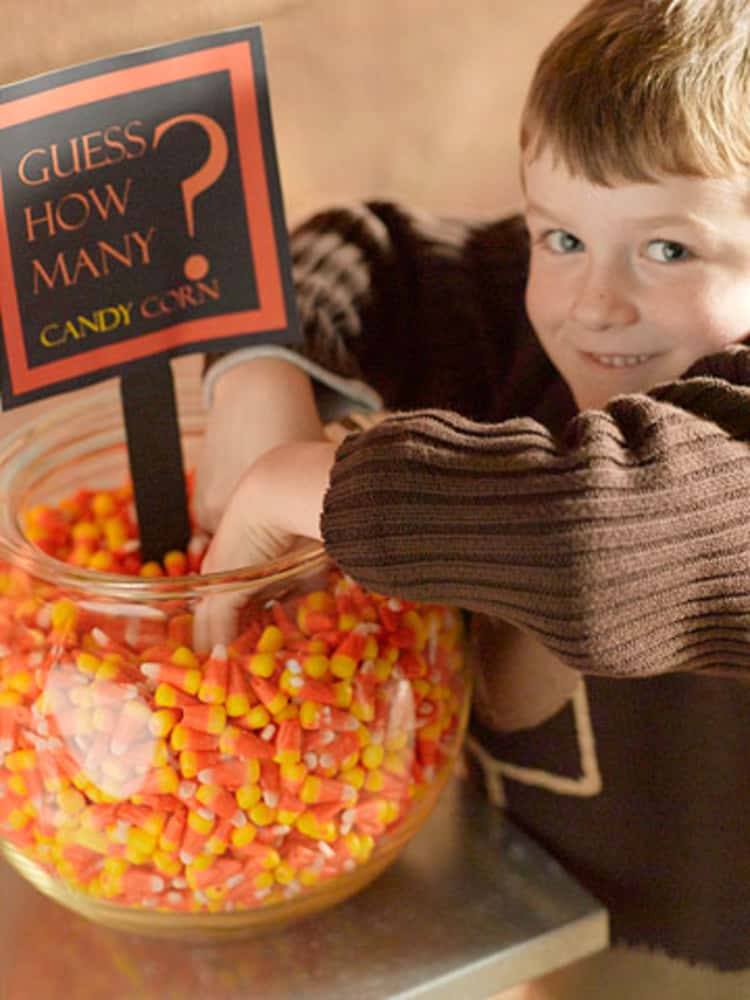 kind with bowl in fingers inside a bowl of candy corn being used for the "Guess How Many" candy corns there are in the bowl