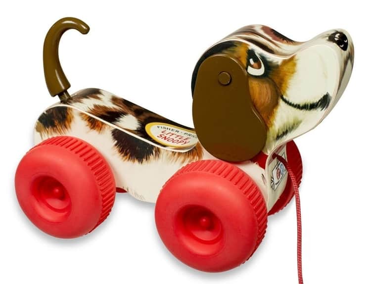 Photo of a vintage inspired pull along dog that is brown and white with red wheels and red string. Makes noise and spins ears.