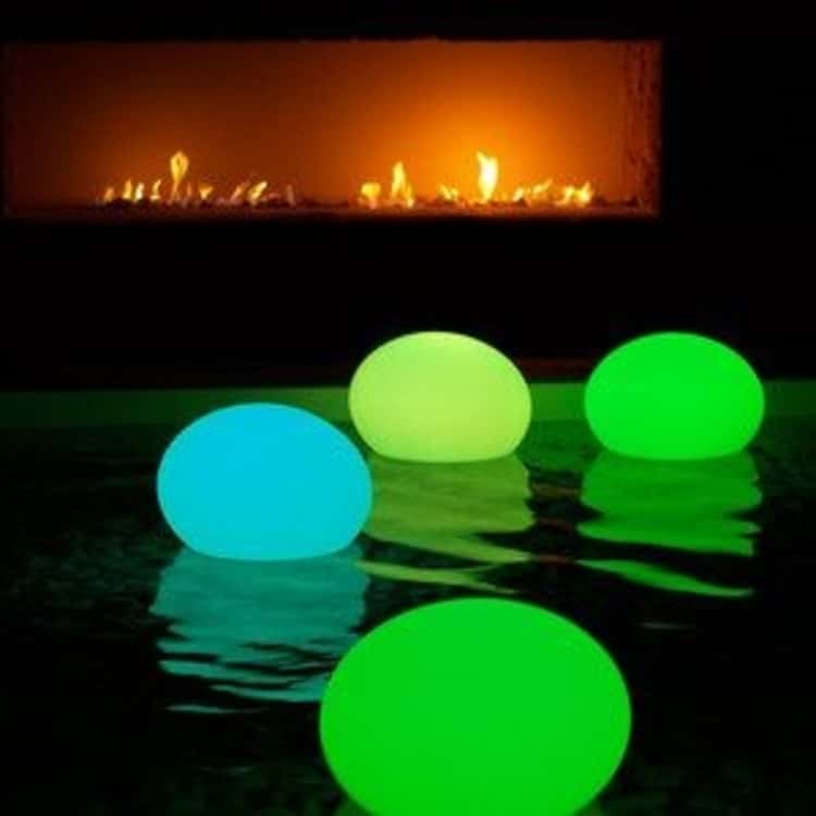 Balloons with glowsticks floating on a pool at night 
